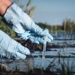 Water pollution concept. Woman scientist takes a water sample from polluted pond.