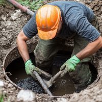 Man cleaning septic tank for sewage removal service. Concept Septic tank cleaning, Sewage removal, Septic system maintenance, Waste disposal, Drain cleaning